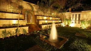 A landscaped garden with a water feature, stone walls, and various plants. - Justa Gurgaon (Gurugram)