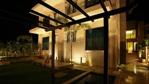 A modern building with a glass facade, outdoor seating area, and a well-lit entrance. - Justa Gurgaon (Gurugram)