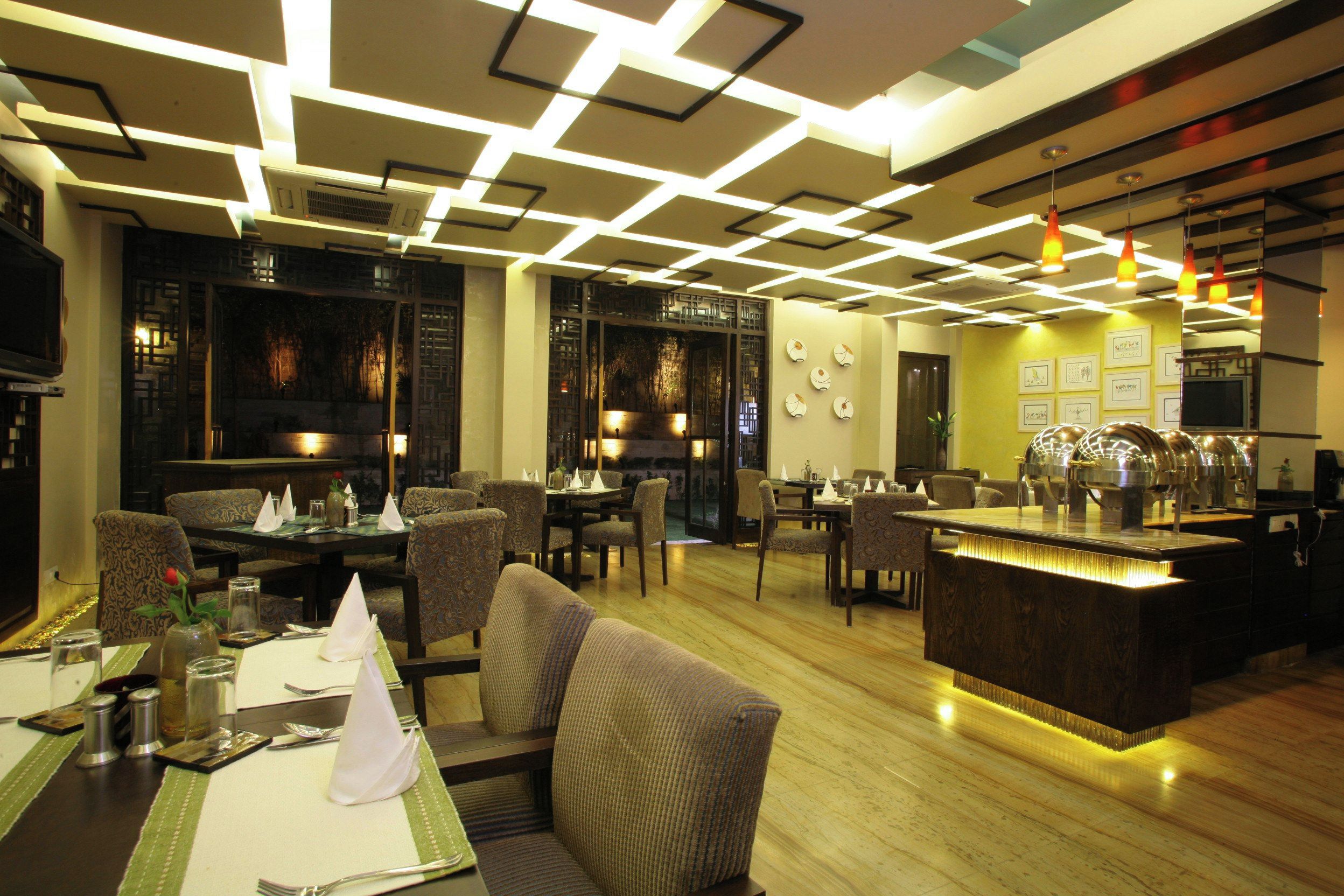 A restaurant with a modern interior, featuring a bar area, dining tables with chairs, and a decorative ceiling.