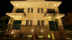 A multi-story building with a symmetrical facade, large windows, and balconies. - Justa Gurgaon (Gurugram)