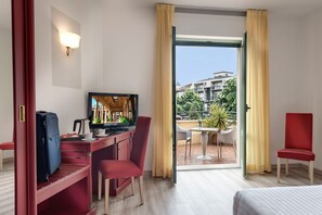 A hotel room with a desk, chair, TV, and a balcony with a table and chairs. - Hotel Da Vinci (Montecatini Terme)