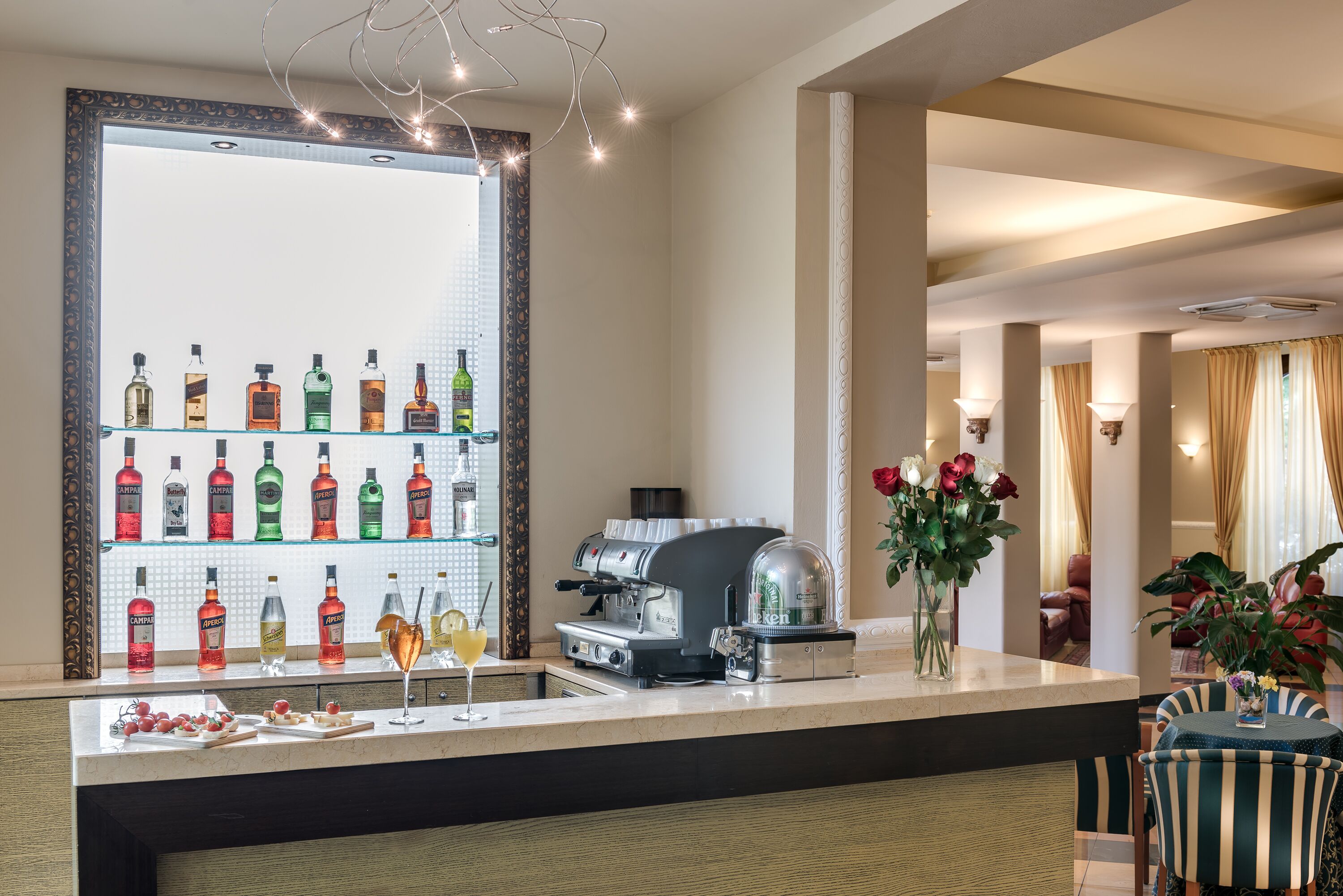 A bar area with a variety of liquor bottles, a coffee machine, and a glass of cocktail.
