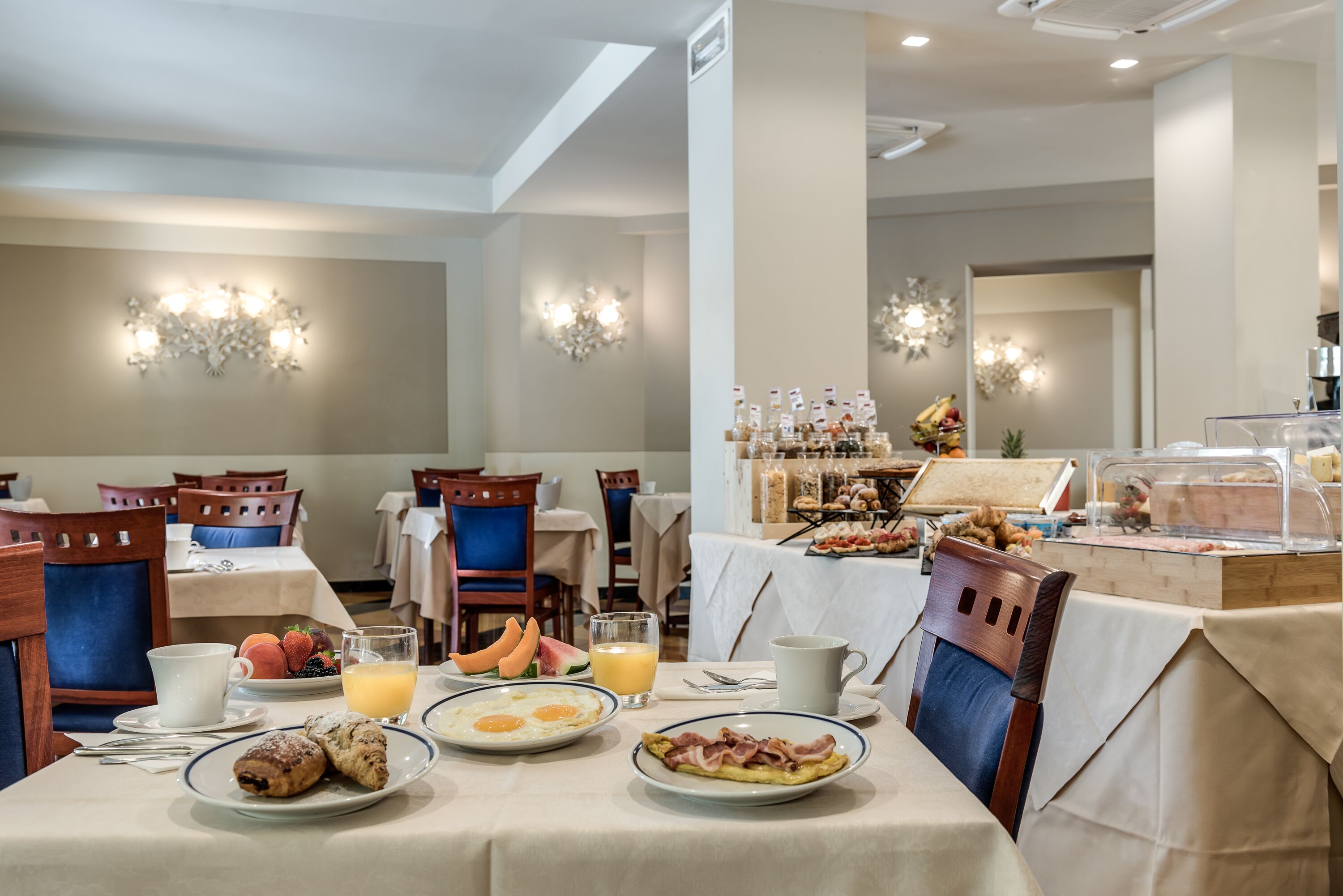 A breakfast buffet with various food items and a seating area with tables and chairs.
