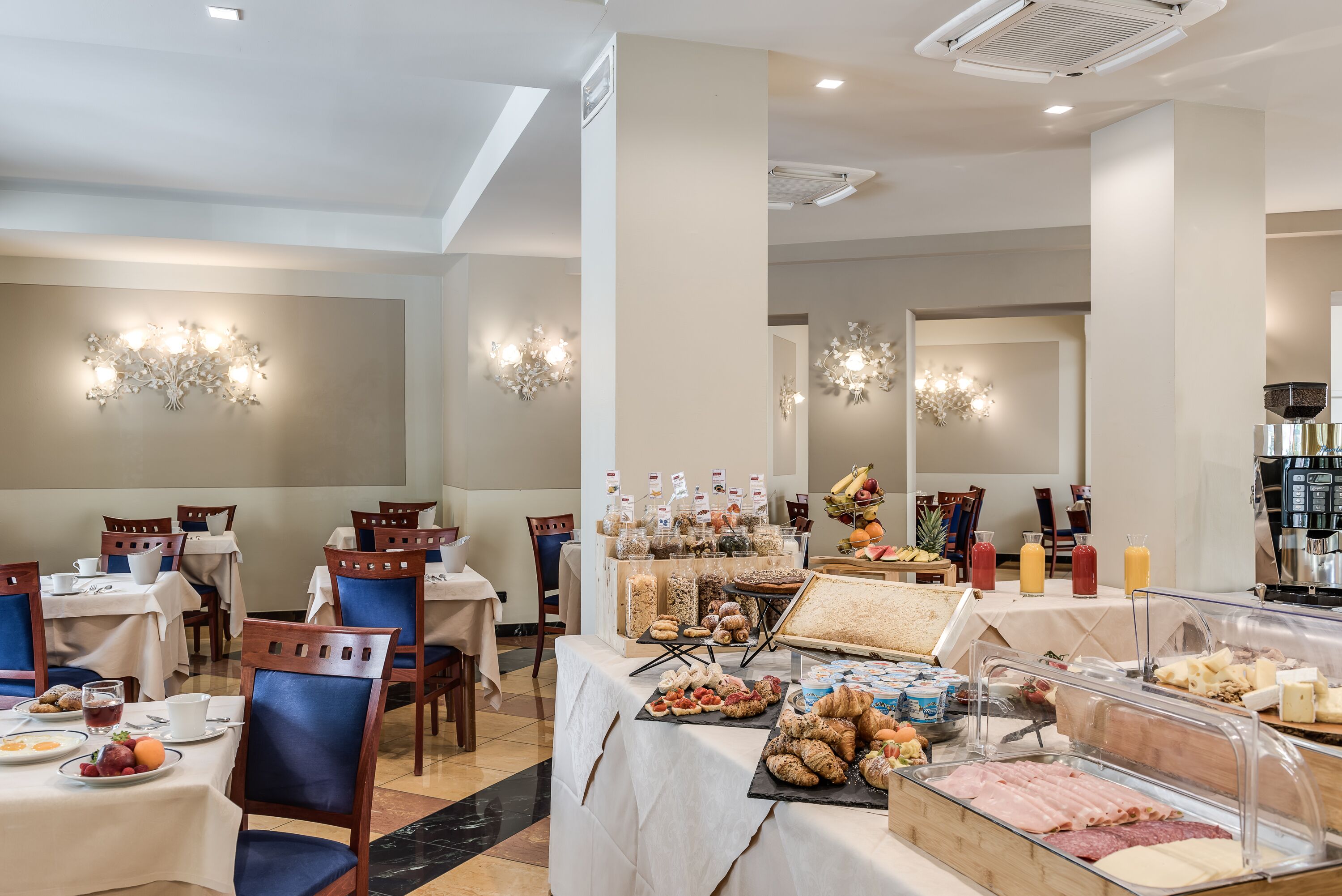 Ein reichhaltiges Frühstücksbuffet mit verschiedenen Speisen und Getränken, präsentiert an Tischen mit Stühlen.