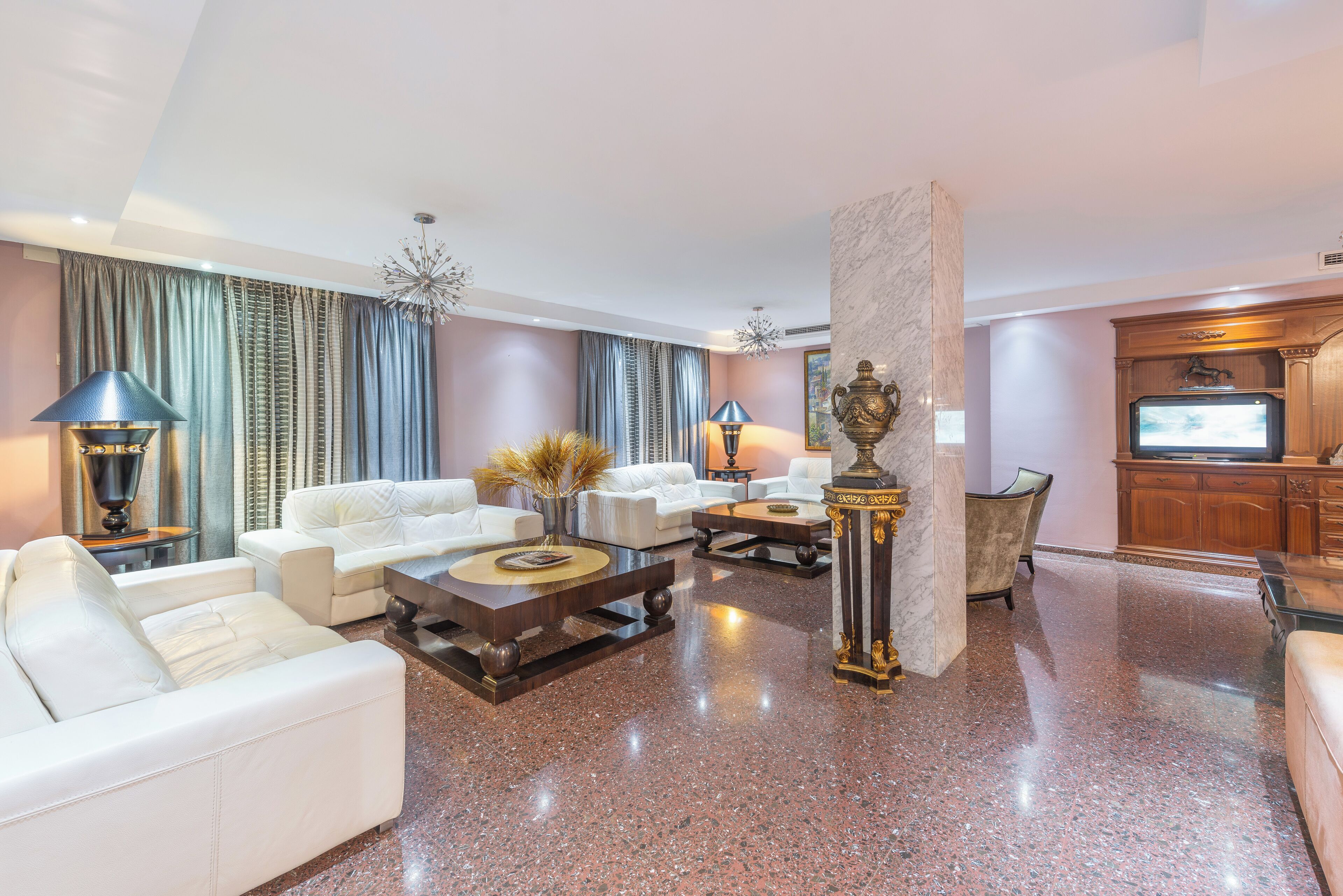 A spacious living room with white sofas, a coffee table, and a fireplace.