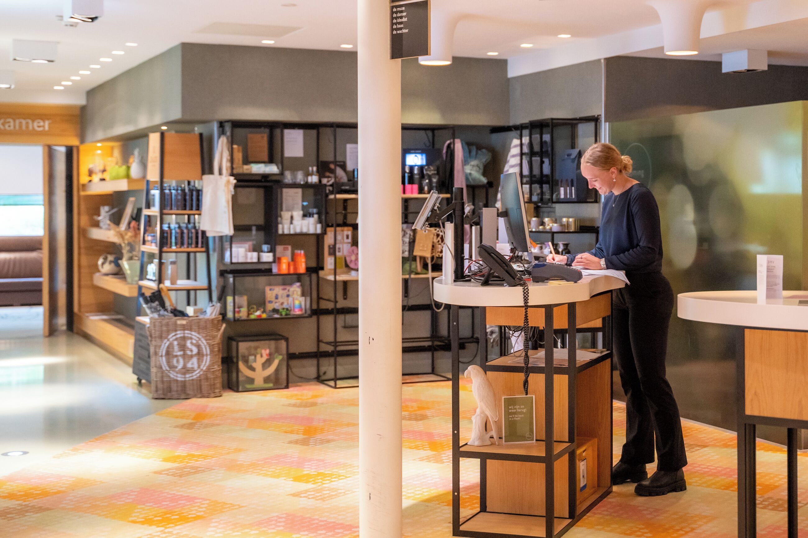 Een modern interieur met een toonbank, planken met producten en een patroon vloer.