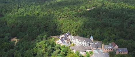 An aerial view of a large estate with multiple buildings surrounded by dense forest.