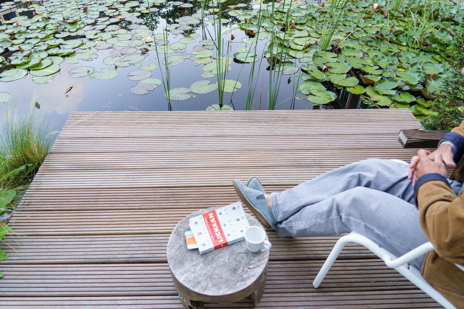 A wooden deck with a round table, a book, and a cup.
