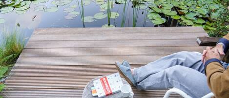 A wooden deck with a round table, a book, and a cup.