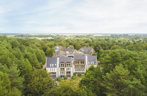 Un immeuble à plusieurs étages, entouré d’une forêt dense, d’où l’on peut admirer une vue dégagée sur le paysage environnant.