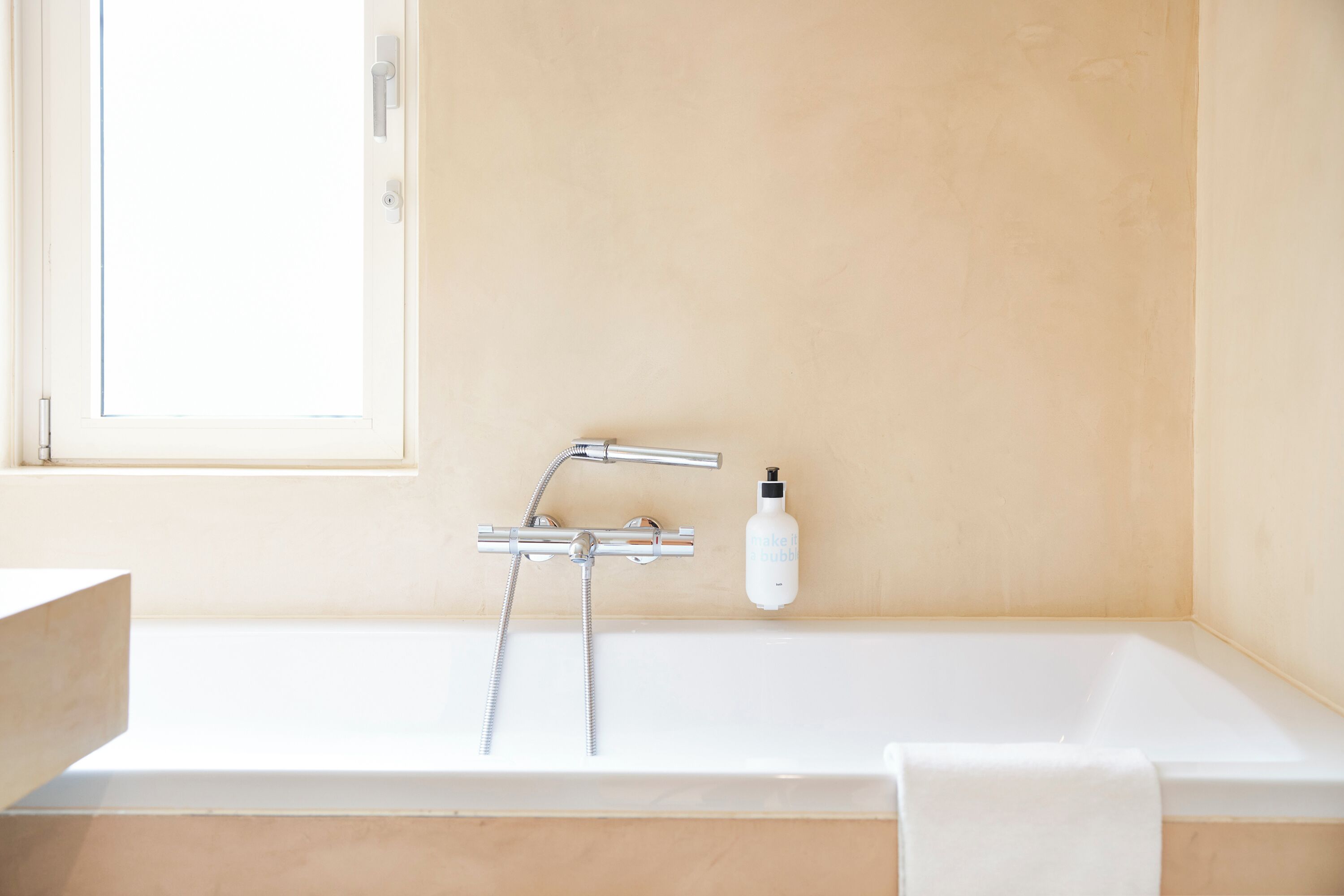 Une salle de bain avec une baignoire, un robinet et une bouteille de shampoing.