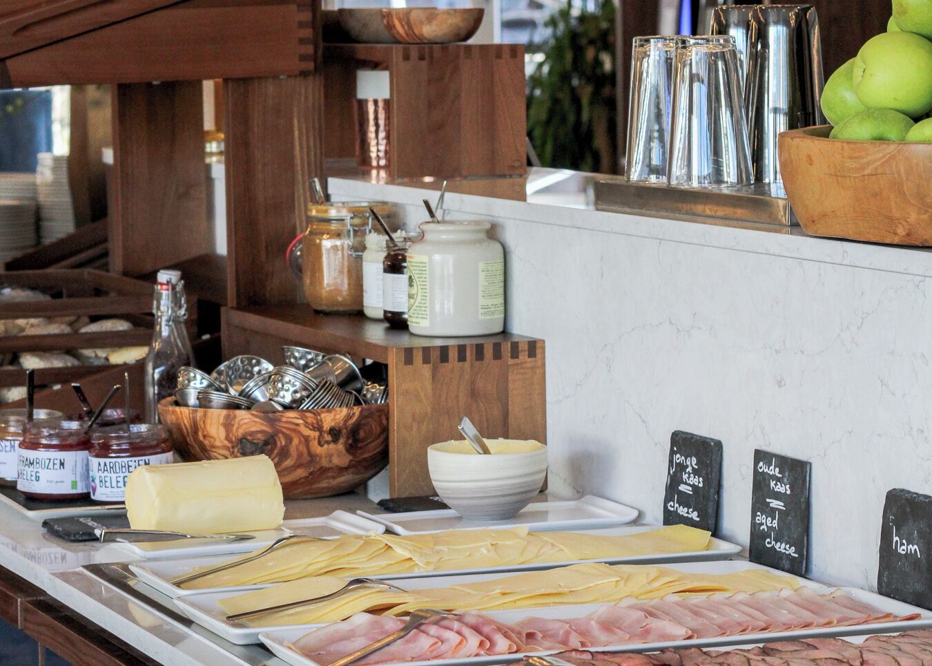 A buffet with various cheeses, meats, and condiments.