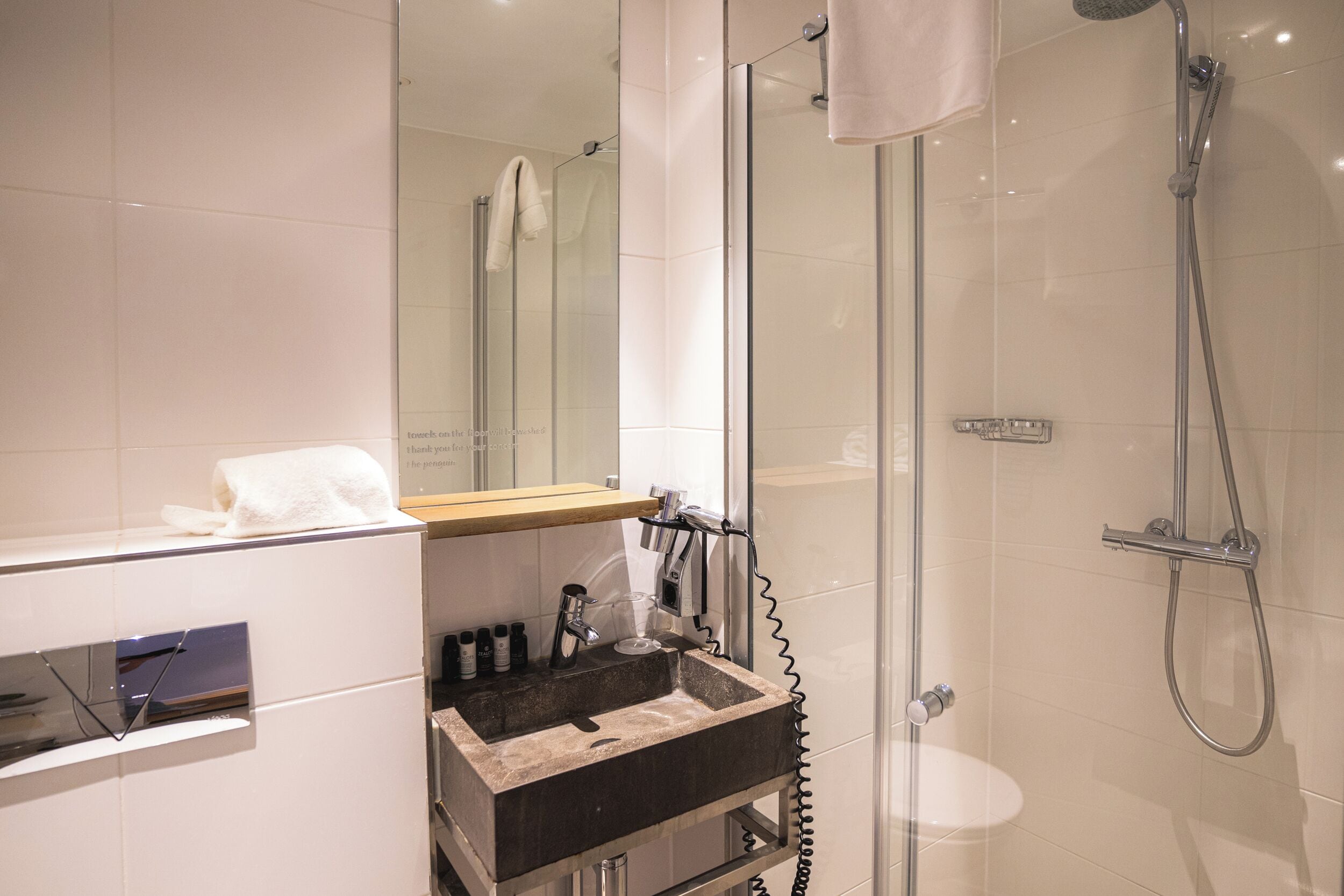 A modern bathroom with a glass shower enclosure, a sink with a towel rack, and a mirror.