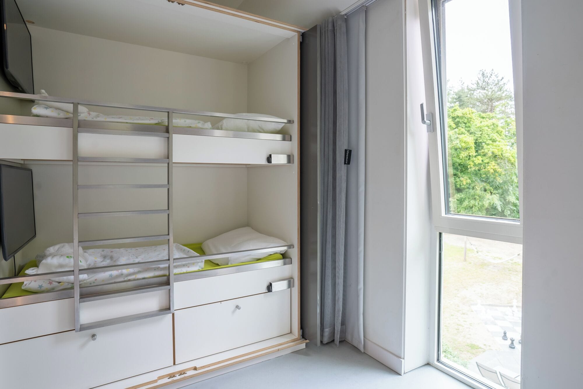 Un dormitorio con literas, un escritorio y un ventanal con cortinas.
