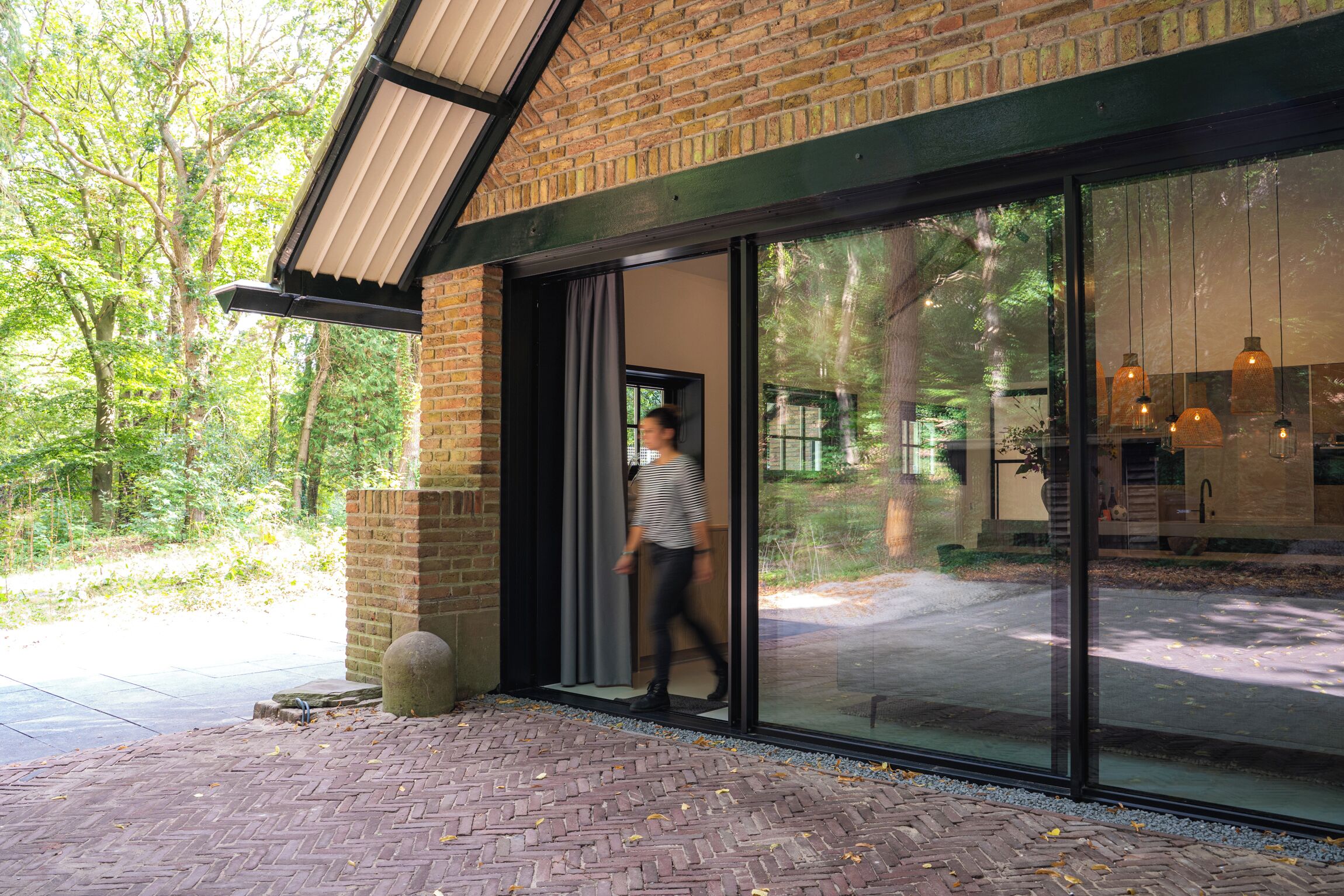 Een modern gebouw met een bakstenen gevel en grote glazen deuren die uitkomen op een terras.