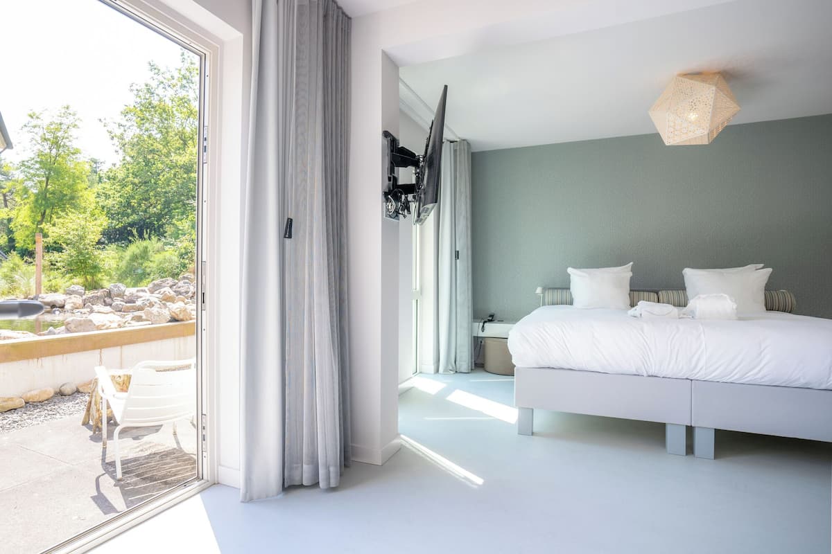 A modern bedroom with a large bed, a bedside table, and a hanging light fixture.
