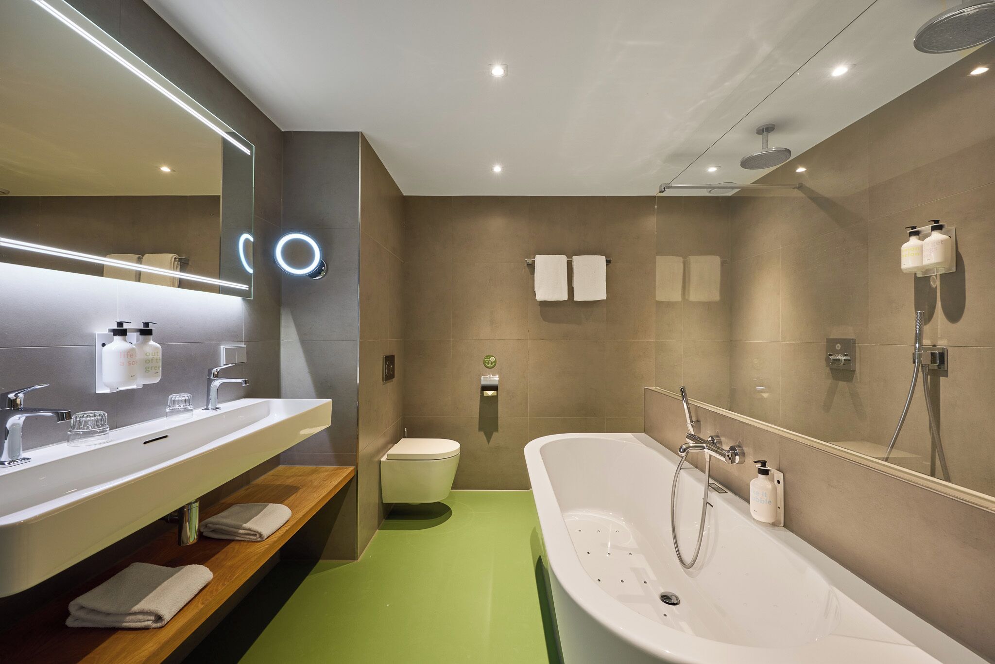 Ein modernes Badezimmer mit einer großen Badewanne, einem Waschtisch mit Spiegel und einer Toilette.