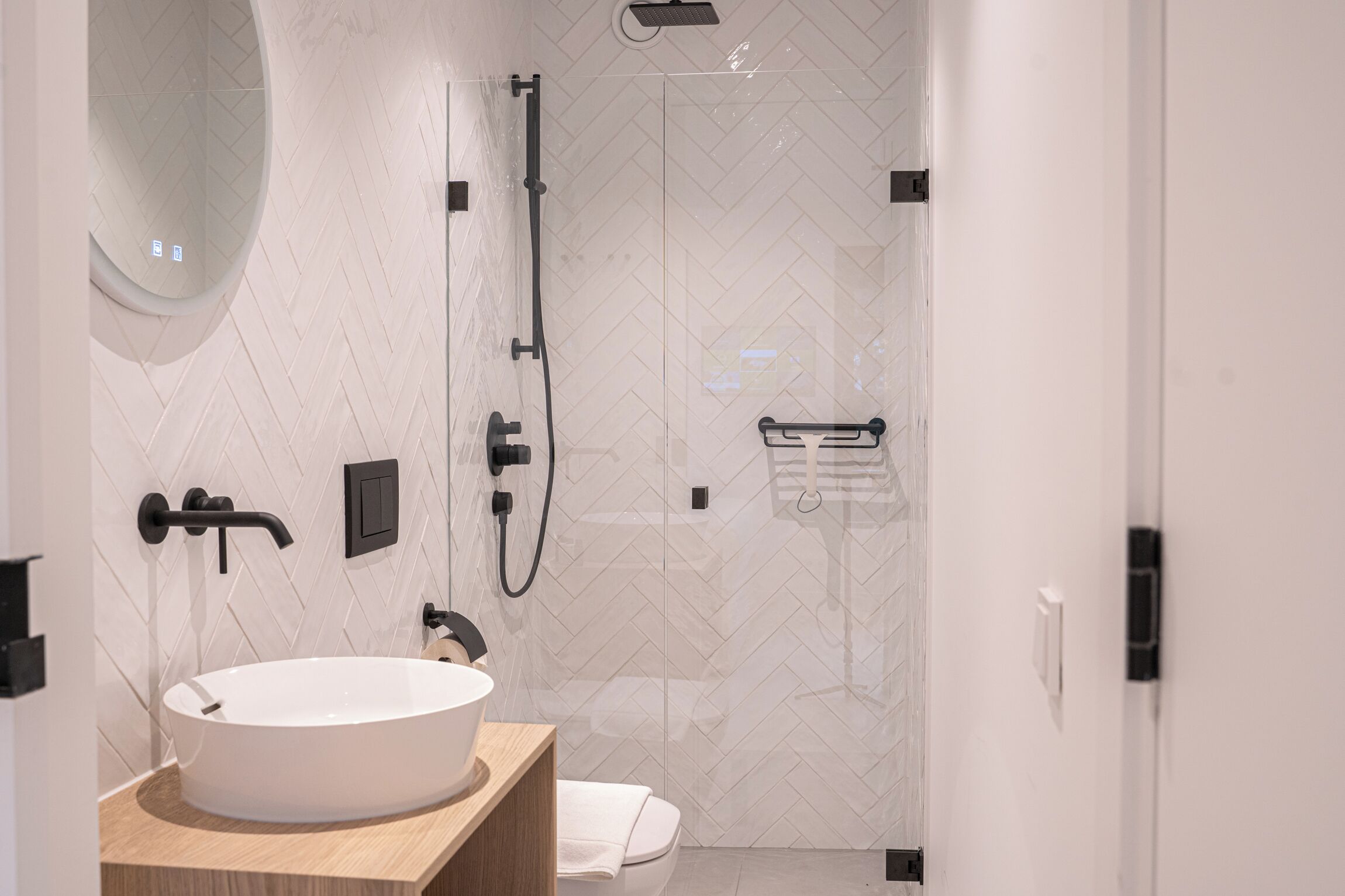 Une salle de bain moderne avec un lavabo blanc, une douche et des toilettes.