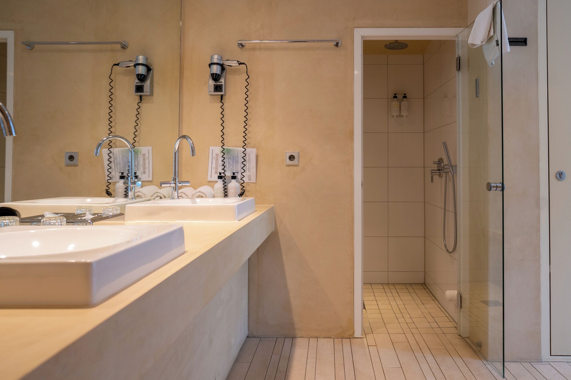 Une salle de bain moderne avec deux lavabos, une douche et un espace douche fermé par des parois de verre.