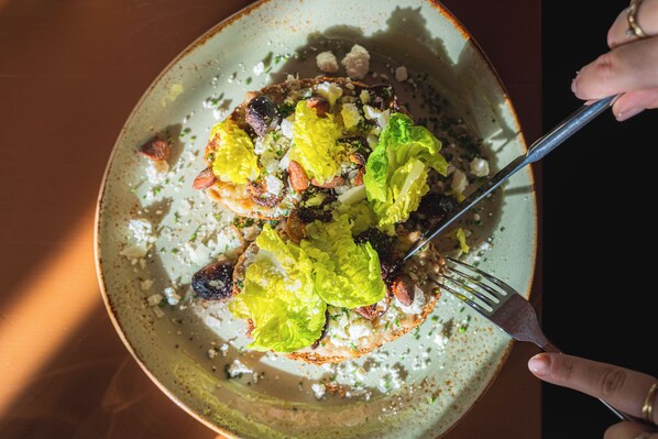 Une assiette contenant une salade composée de laitue, de noix et de fromage émietté.