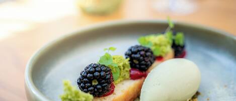 A dessert plate with a scoop of ice cream, blackberries, and a piece of cake.