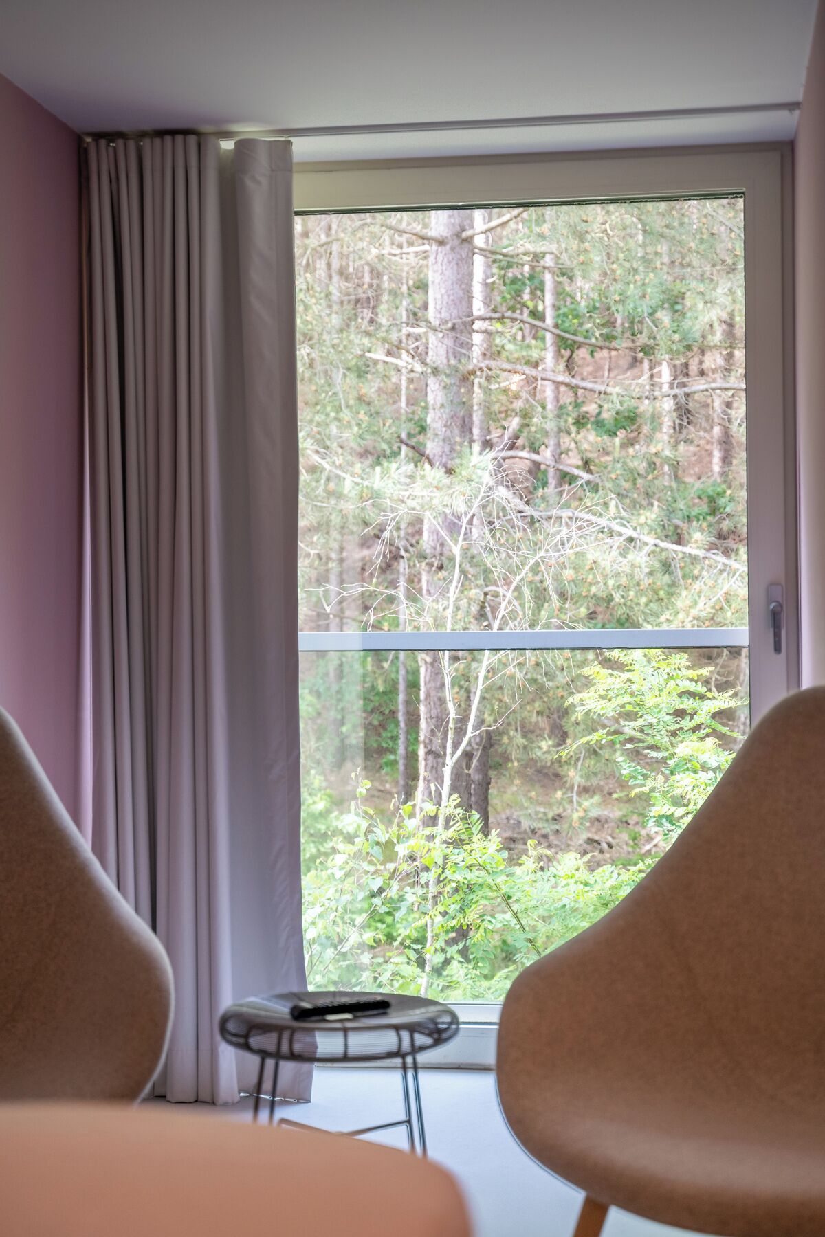 A room with a large window, a small table, and two chairs.