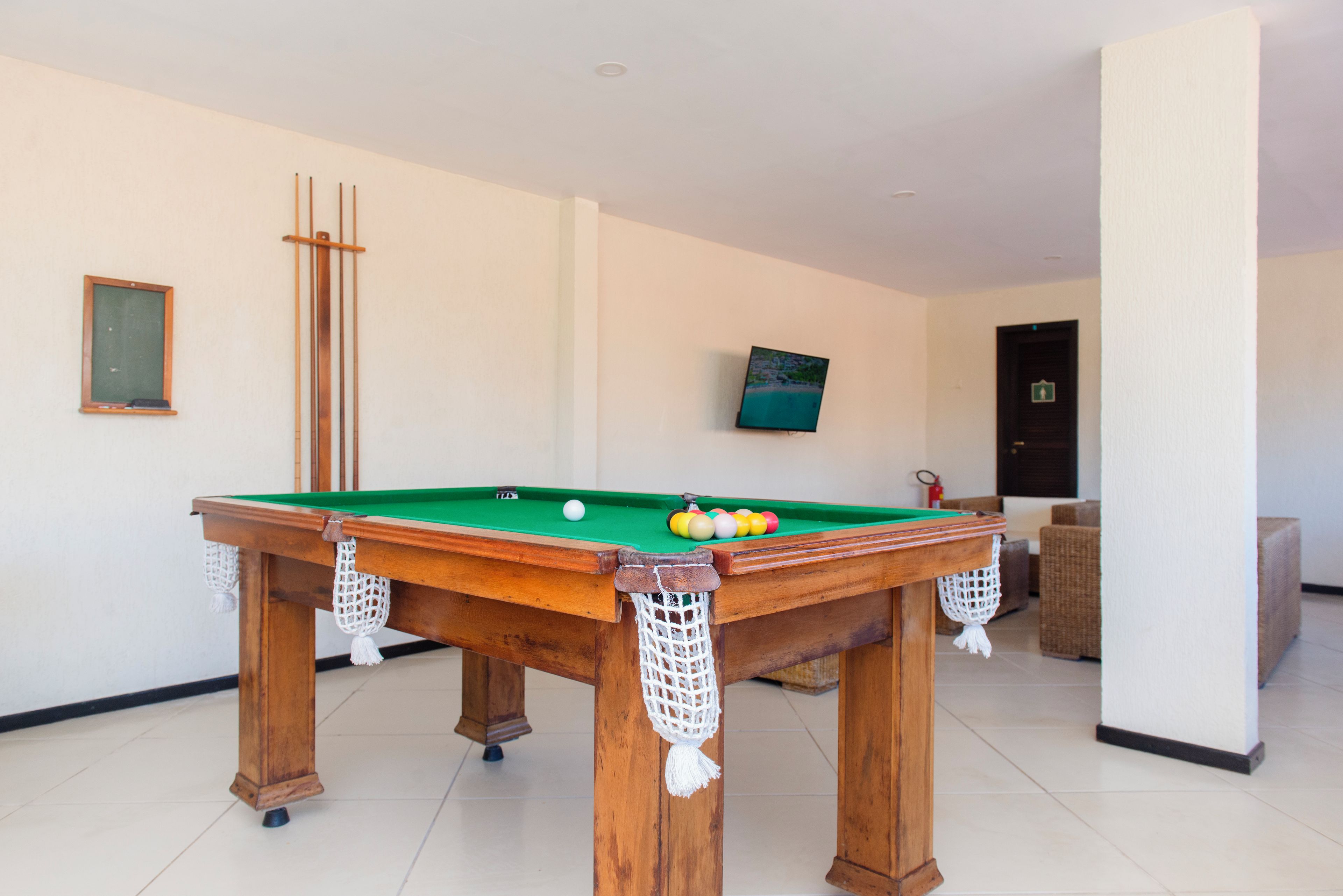 A pool table with balls, a framed picture, and a television on the wall.
