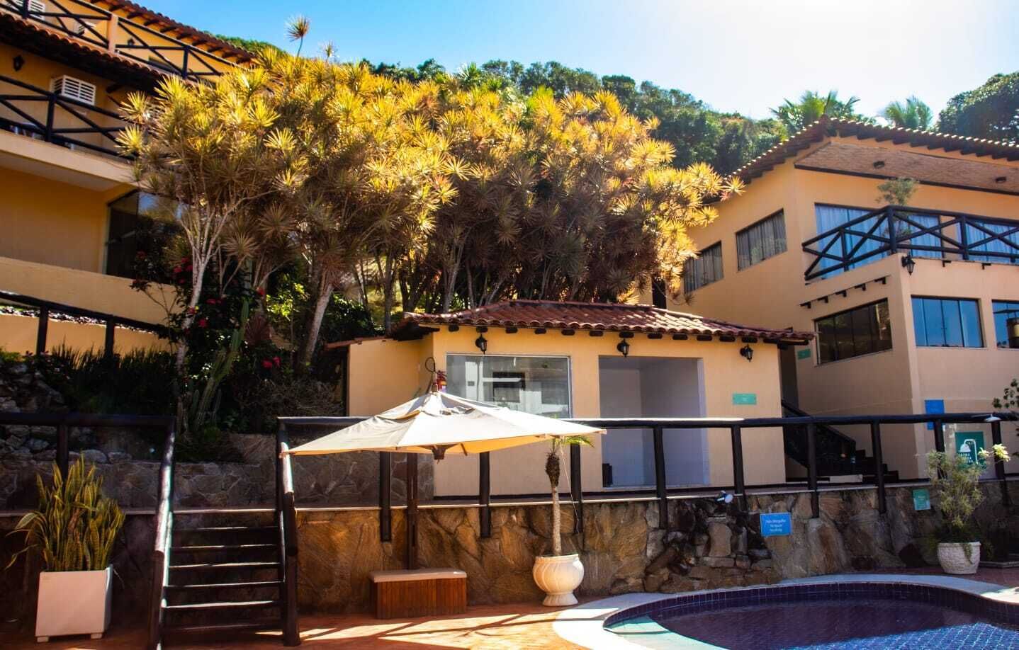 A pool area with a stone wall, a wooden bench, and a small umbrella.