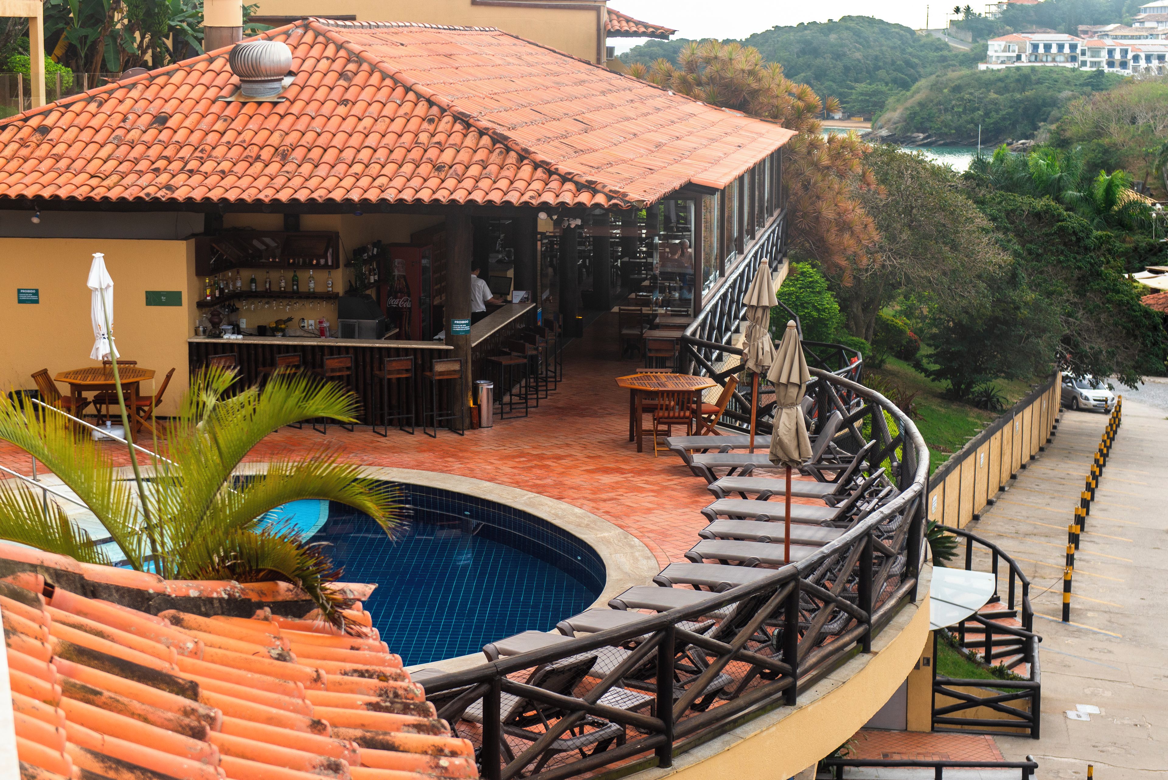 A poolside area with a bar, lounge chairs, and a view of a hillside.