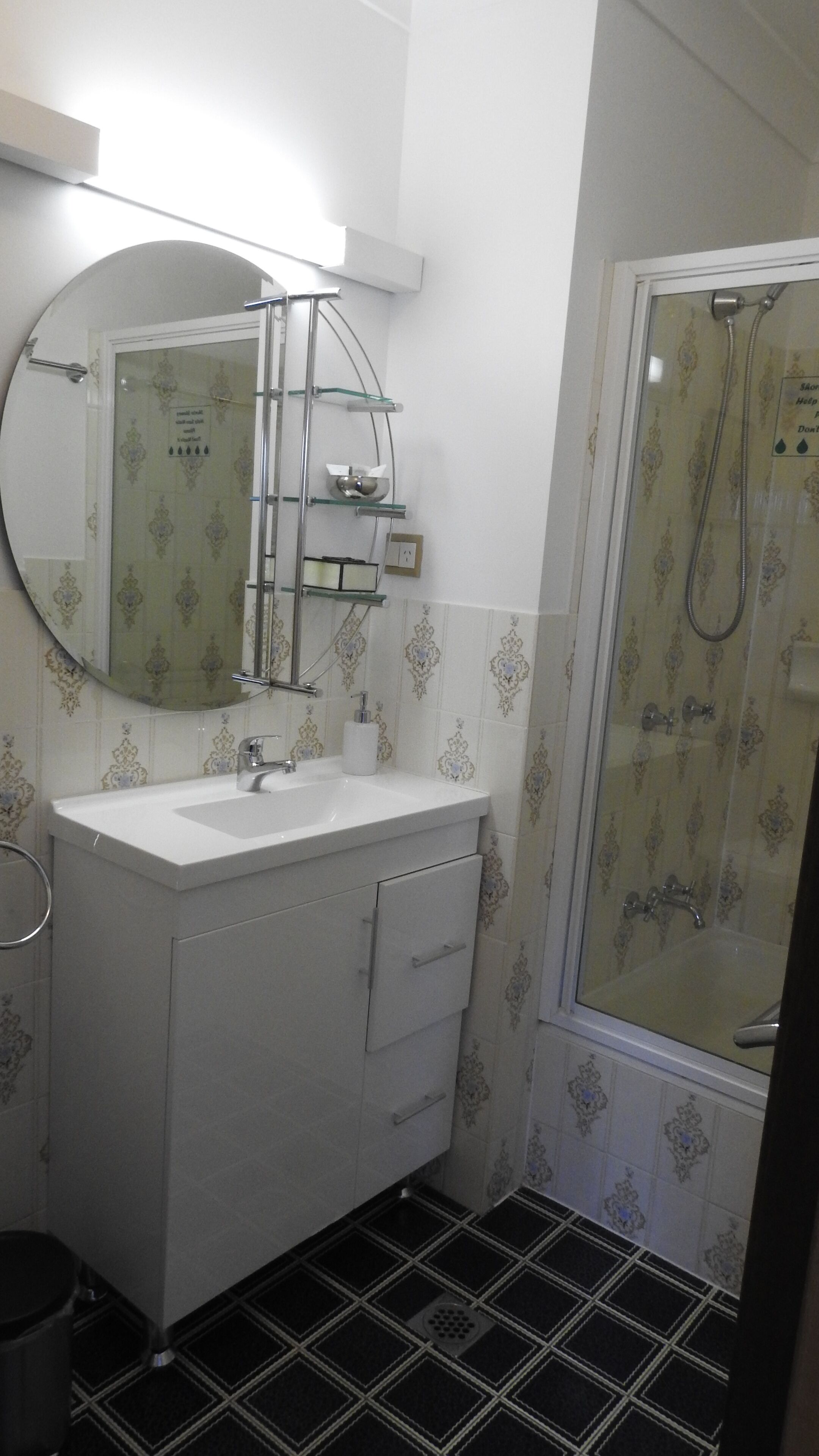 Un baño con lavamanos blanco, espejo y ducha.