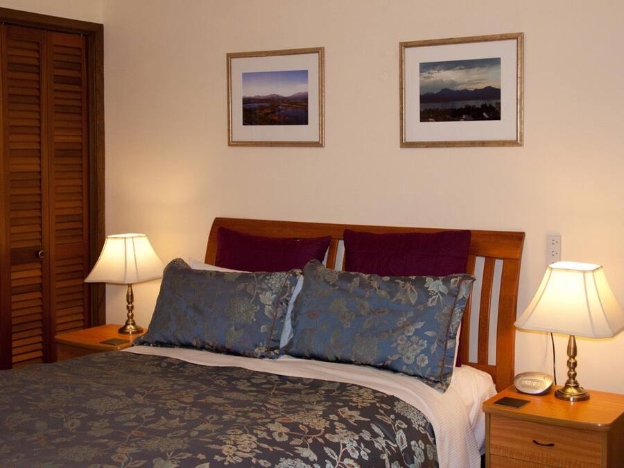 A neatly made bed with floral bedding, two bedside lamps, and two framed pictures on the wall.