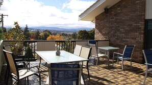 A patio with a table and chairs, a brick wall, and a view of the landscape. - Bathurst Heights B&B (Bathurst)