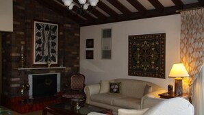 A cozy living room with a fireplace, a sofa, a coffee table, and a lamp. - Bathurst Heights B&B (Bathurst)