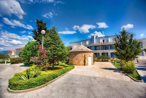A stone building with a small door, surrounded by well-maintained greenery and a clear blue sky.