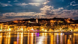 Un pueblo costero de noche con edificios iluminados y una imponente aguja de iglesia.