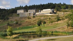 Un ensemble immobilier moderne comprenant plusieurs bâtiments, un étang et un sentier.