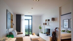 Un salon moderne avec un canapé, une table basse, un téléviseur et un sac de golf.