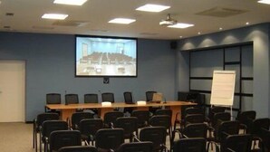 Une salle de conférence équipée d’une longue table, de nombreuses chaises, d’un écran de projection et d’un tableau blanc.