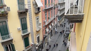 Une vue de rue d’une ville européenne, avec des immeubles à plusieurs étages, des balcons et des piétons.