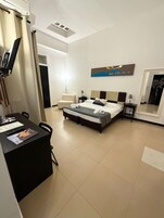Una camera d'albergo con un letto, una scrivania, una sedia, una lampada e un quadro appeso al muro.