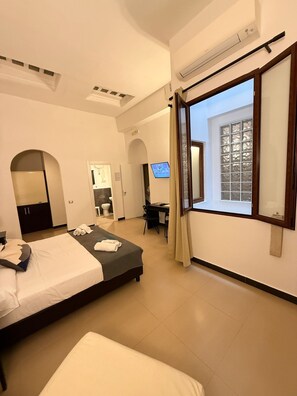 Une chambre d’hôtel moderne, dotée d’un grand lit, d’un bureau et d’une télévision.
