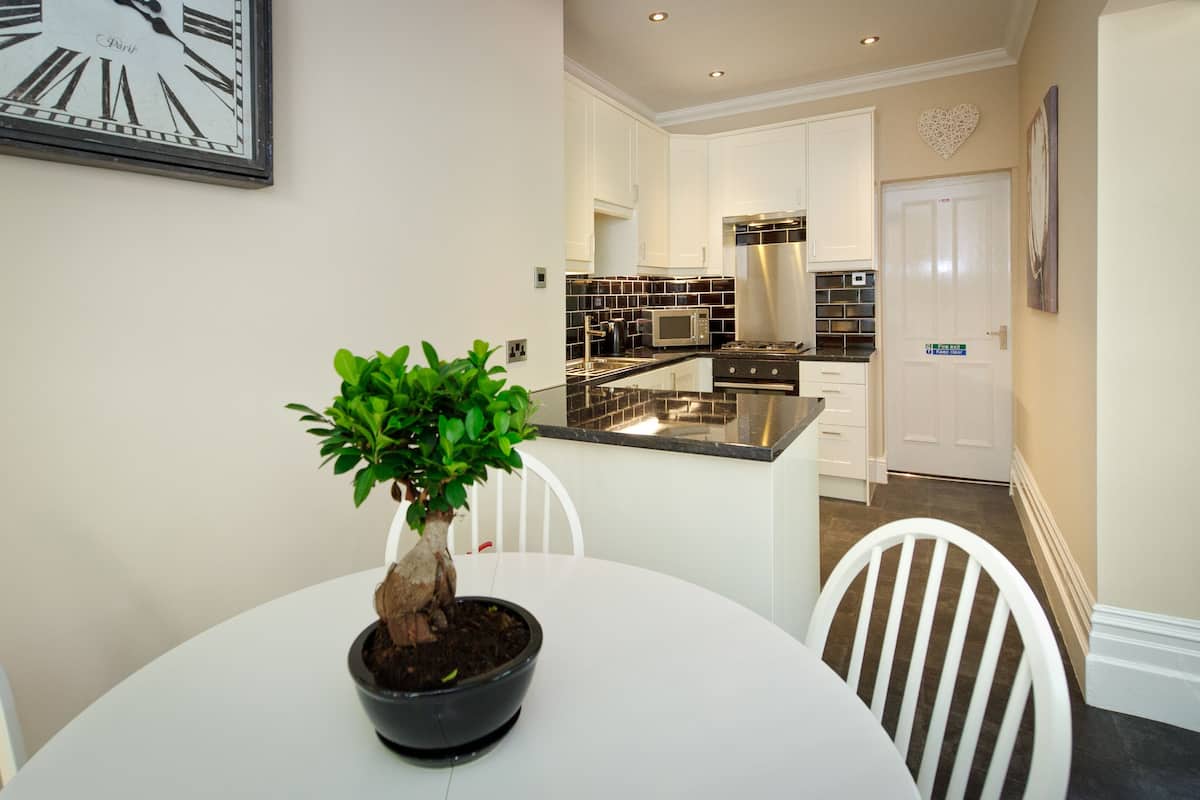 A modern kitchen with white cabinets, a stainless steel stove, and a black countertop.