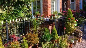 A brick house with a garden, a metal fence, and potted plants. - Cheshire Hospitality Ltd T/A Lennox Lea Studios & Apartments (Sale)