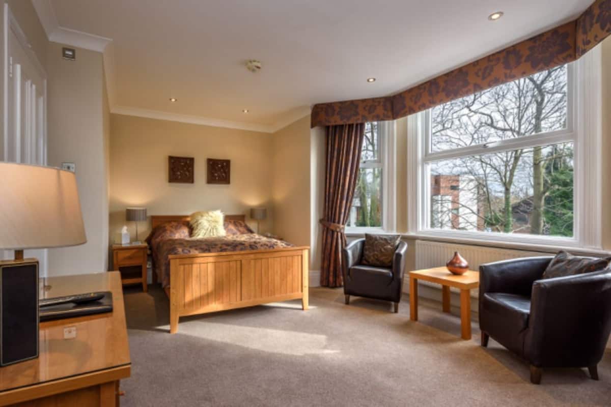 A hotel room with a bed, a desk, a chair, and a window with curtains.