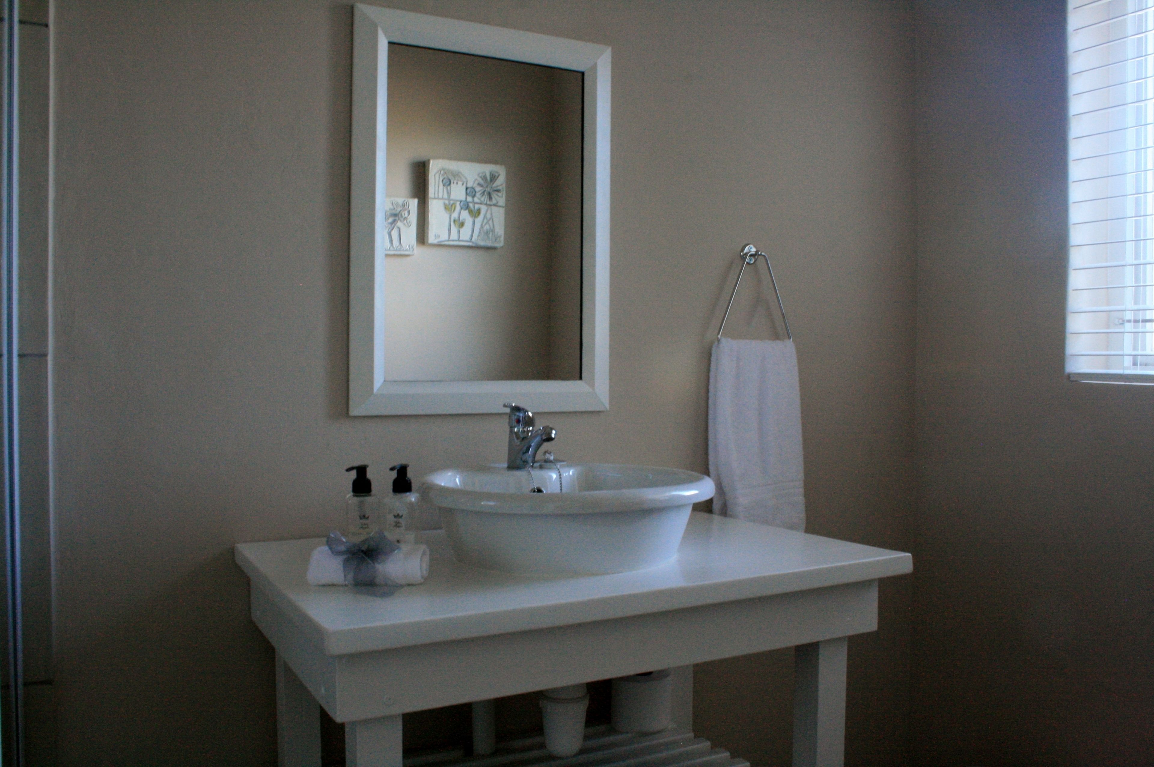 A bathroom with a white sink, a mirror, and a towel rack.