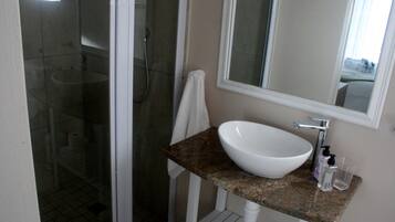 Une salle de bain avec un lavabo blanc, un miroir et une douche.