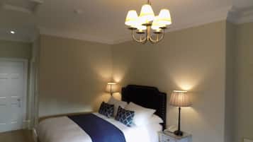 A hotel room with a bed, bedside lamps, and a chandelier.