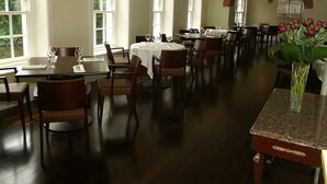 A spacious dining area with multiple tables and chairs, large windows, and a brick archway. - Flynns of Termonfeckin (Termonfeckin)