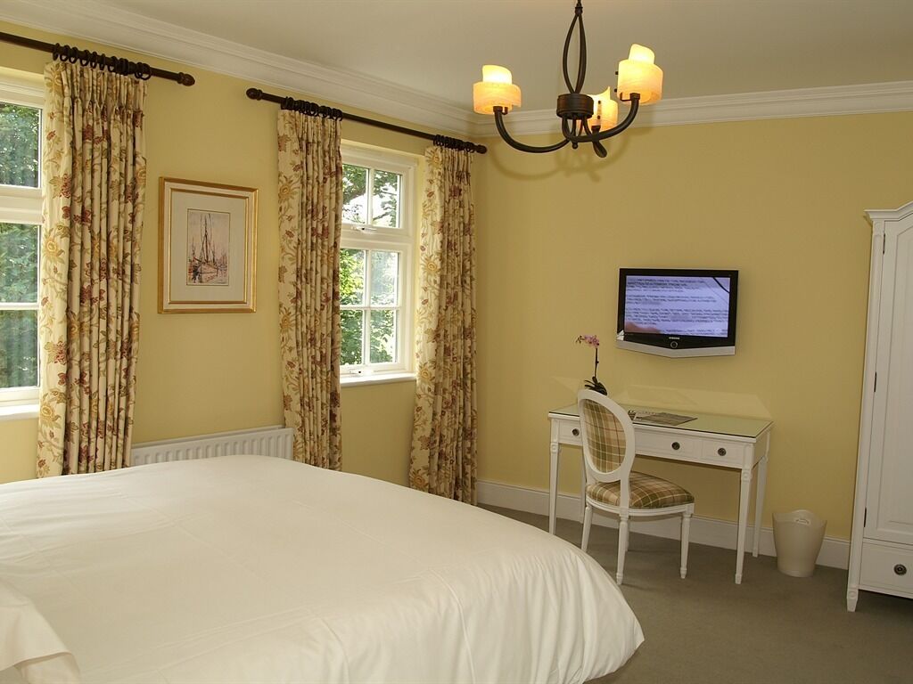 Une chambre à coucher avec un grand lit, un bureau avec une chaise, une télévision et une armoire.