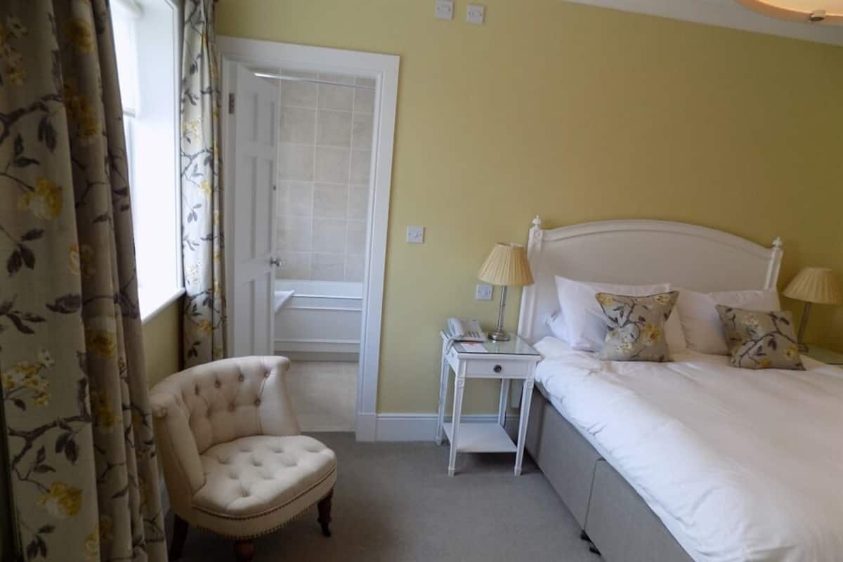 A bedroom with a bed, a bedside table, a chair, and a door.
